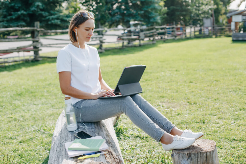 Workation outdoor. Woman working on laptop in park. Distant remote job work during quarantine coronavirus covid-19. Student studying learning online.