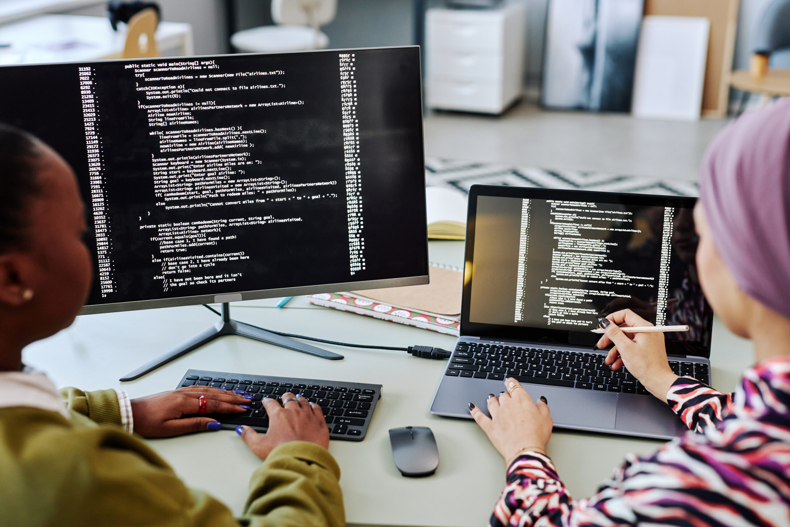 High angle view at two people writing code and reviewing project together in software development office