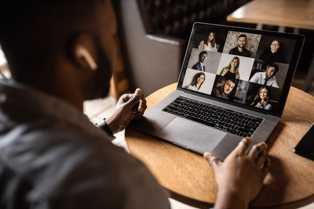 Young African American businessman looks into the laptop screen, speaks by video communication with his colleagues. Business entrepreneur, sitting in an office, pondering a business plan.