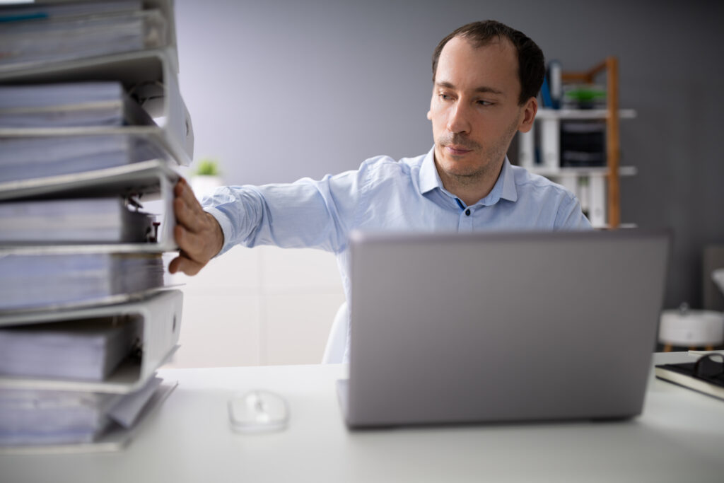 Businessperson Pushing Paper Documents Away And Working With Digital Documents On Computer Instead